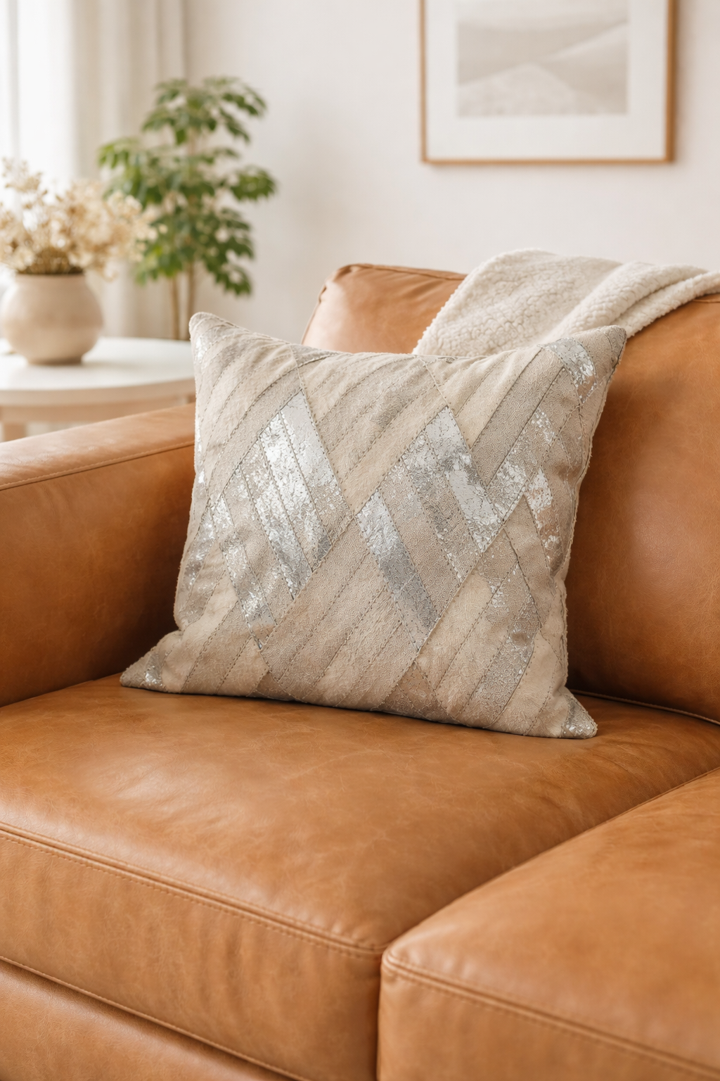 Decorative pillow on a brown leather sofa with a neutral color scheme.