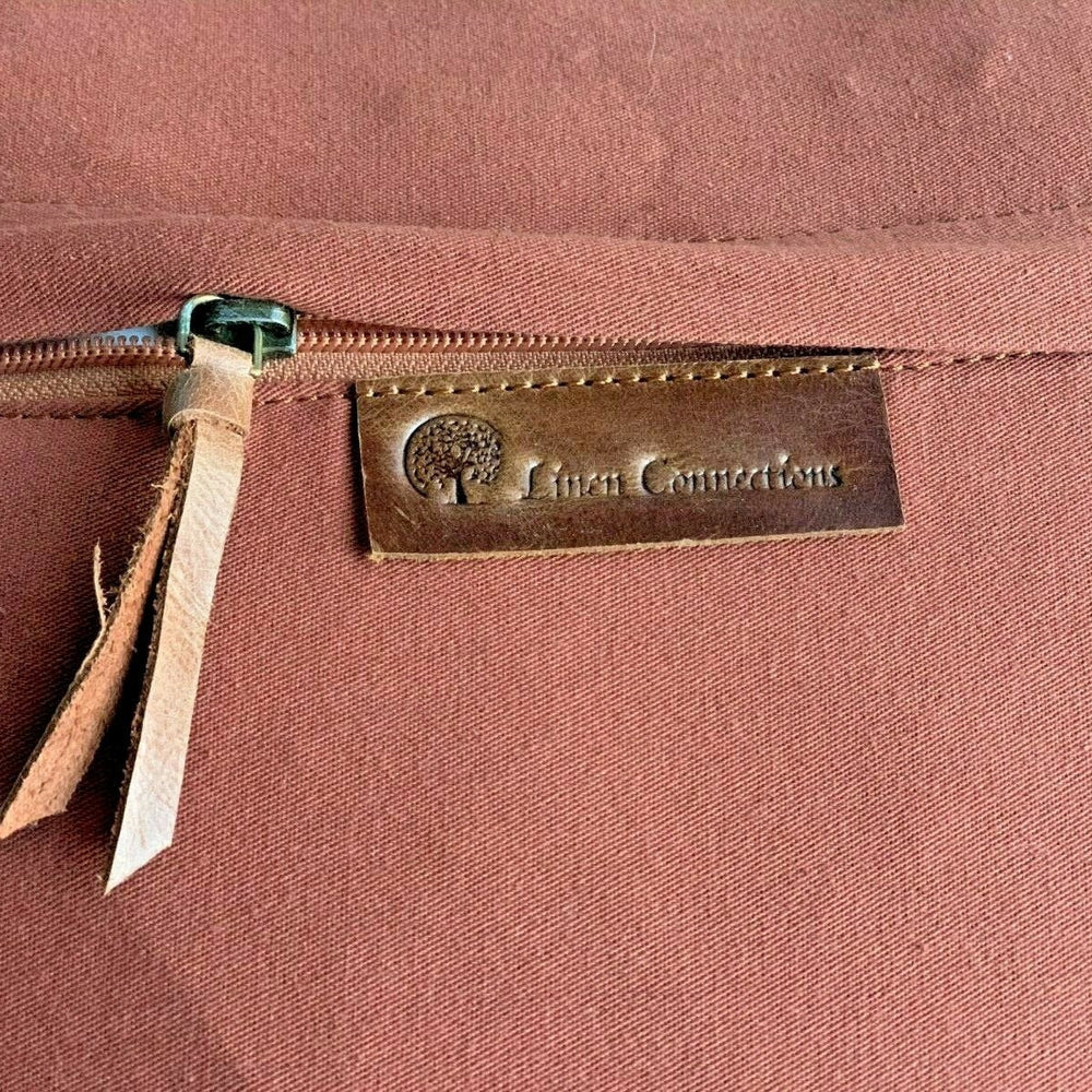Flat lay of handmade rustic farmhouse pillow cover – tan leather and natural canvas fabric.