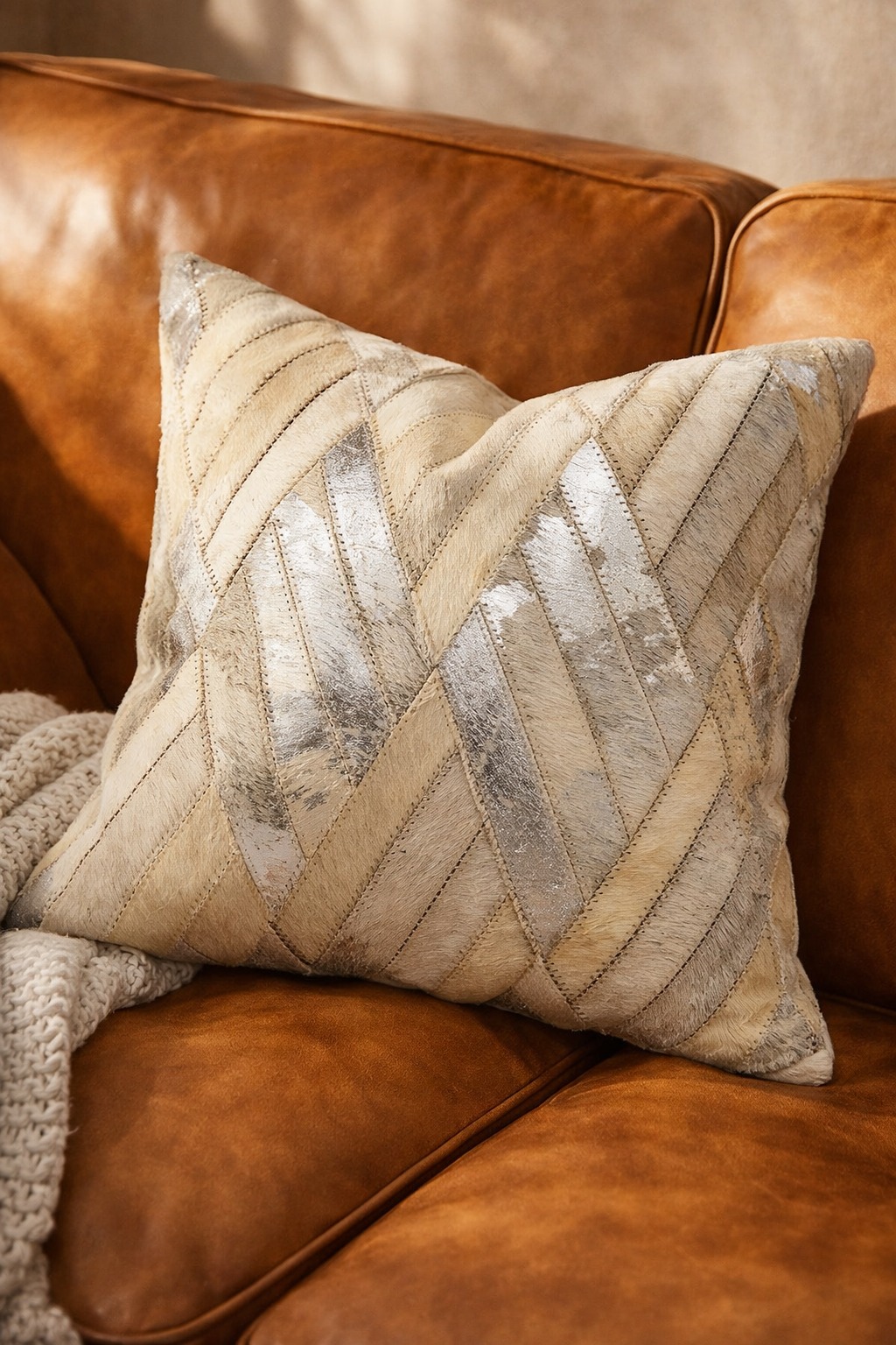 Decorative pillow with a zigzag pattern on a brown leather couch.