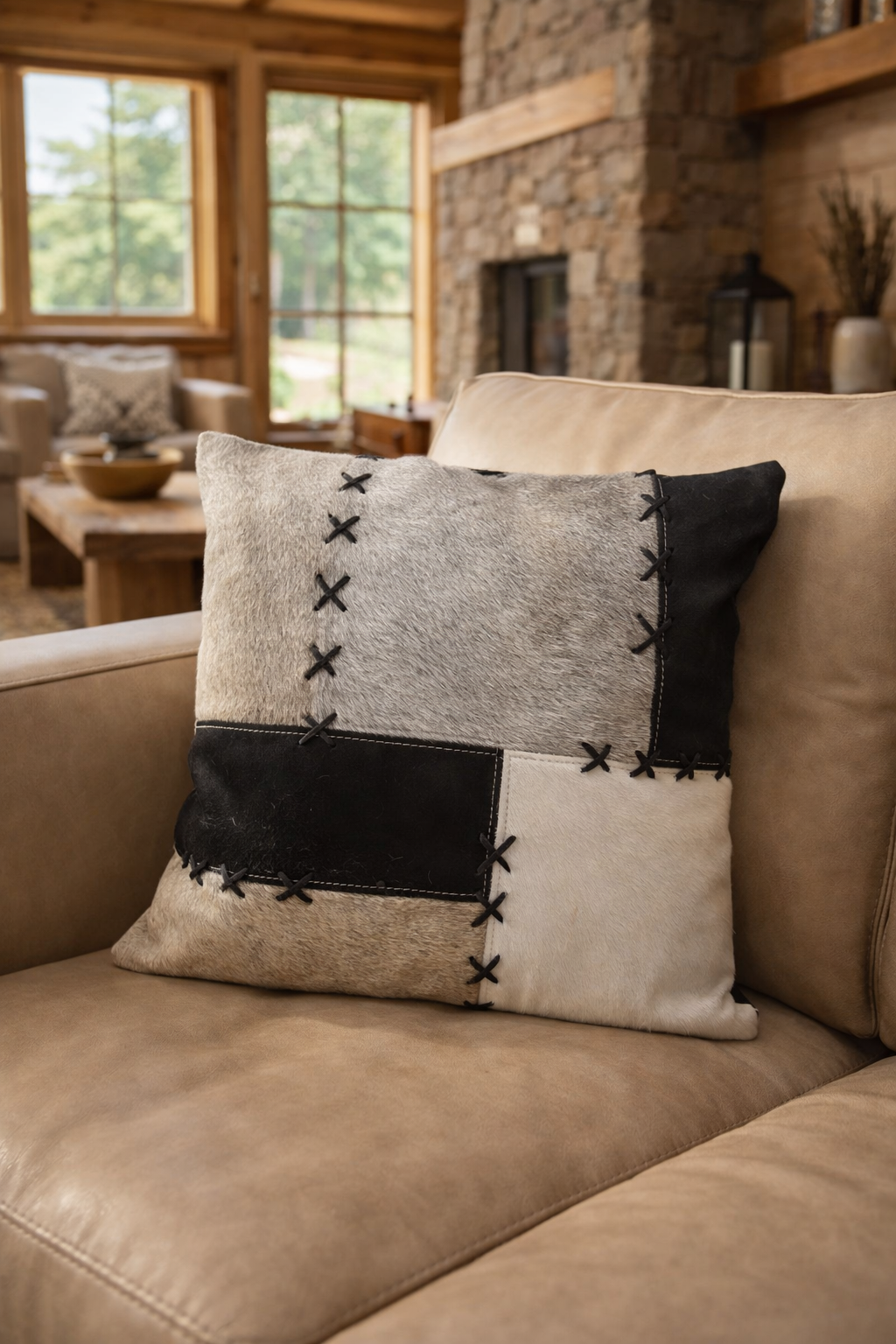 Patchwork cowhide cushion cover with black panel and X stitch lacing in modern rustic lounge