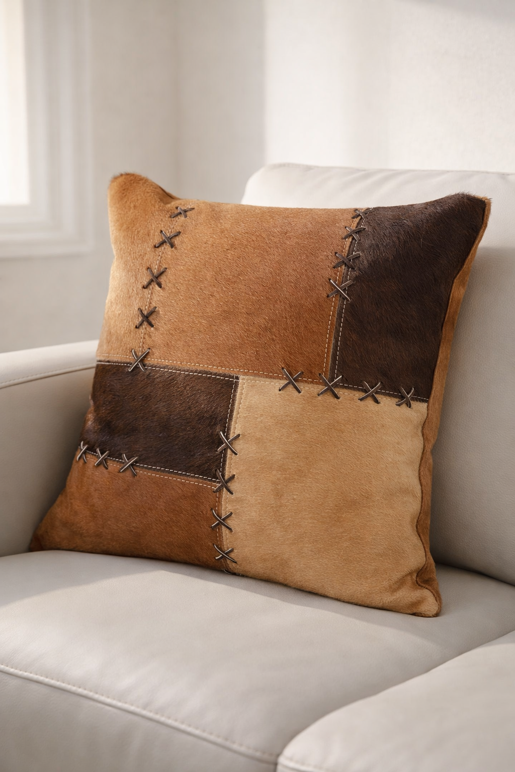 Handcrafted cowhide patchwork pillow cover with cross-stitch lacing detail
