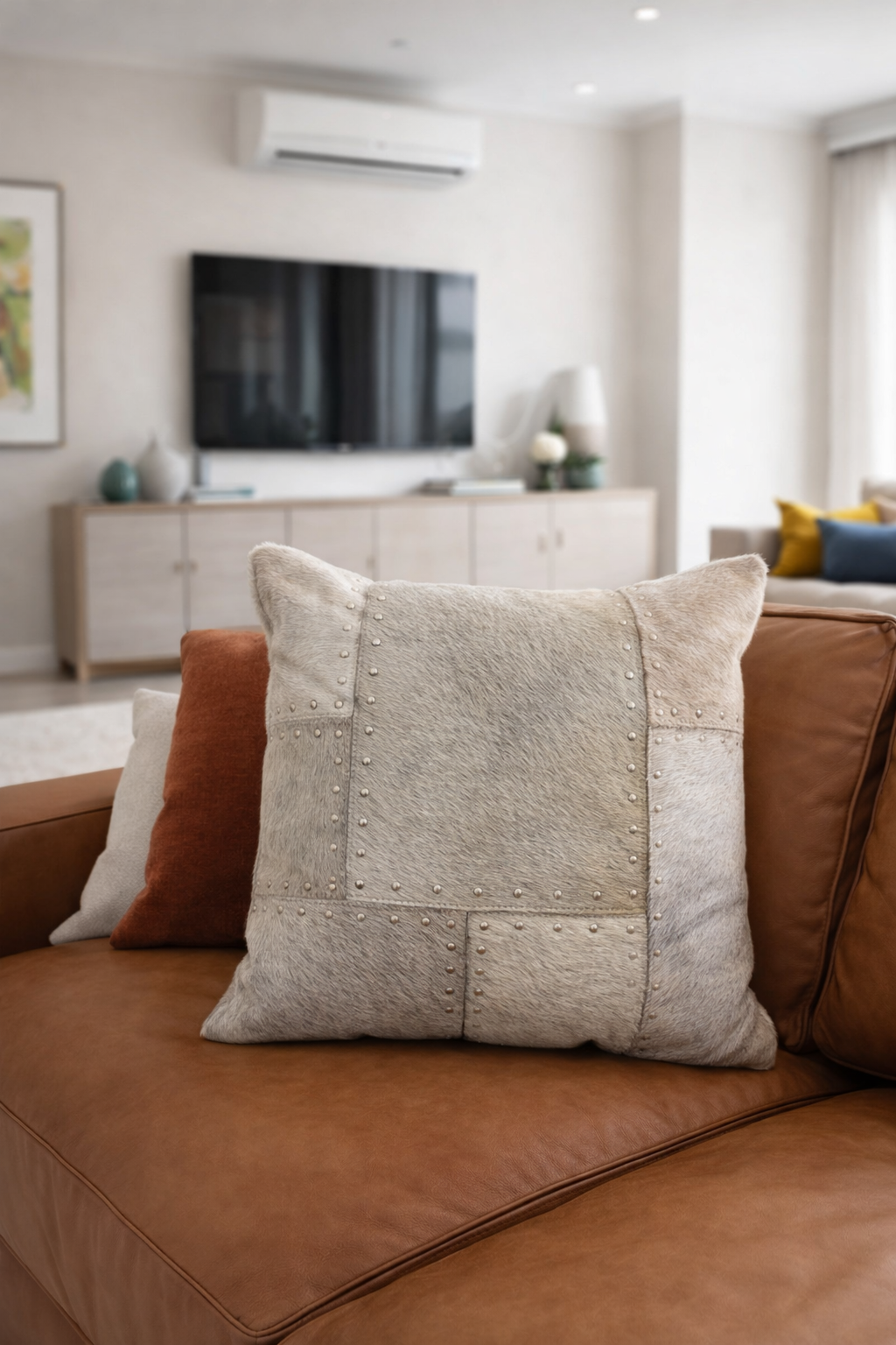 Cowhide leather cushion cover 40x40cm with studded patchwork design on a leather sofa